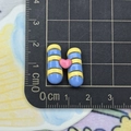 Macro shot of 2cm blue-yellow striped resin H-shaped accessory with pink heart detail - Telescope