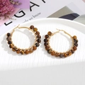 Detail of wire-wrapped gold hoops with natural brown stone beads on white ceramic tray - Black Brown Beads