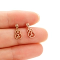 Orecchini a perno a chitarra in oro rosa con design traforato mostrati sul dito - Oro rosa