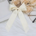 Beige satin bow hair clip with streamers on soft white fur and elegant accessories - Beige