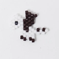 Macro shot of handmade pixelated dinosaur bead charm for jewelry making accessories - White