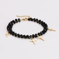 Detalle de la pulsera de cuentas negras con varios colgantes de cruces doradas - Pulsera