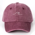 Detailed close-up of burgundy washed cotton fabric and wave embroidery on the baseball cap - Burgundy