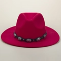 Dettaglio cappello fedora magenta con cintura in pelle nera e fibbie metalliche incise - Rosso