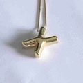 Detailed close-up of a polished gold letter X pendant with elegant matching chain - Letter X