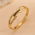 Detalle macro de la pulsera bañada en oro de 18 quilates con pequeñas piedras negras - Brazalete Geométrico Dorado con Circonia Negra (H612)