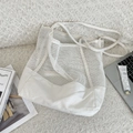 Dettaglio di una borsa tote in rete bianca con base in tela su un tappeto di peluche - Bianco