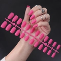 Pink matte long square fake nails shown on hand with silver rings and on display board - Matte Pink