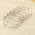 Detail of five stackable silver bangles with minimalist round bead charms on textured surface - Inner Diameter 60mm / 5 Rings Set / Steel