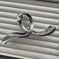 Macro shot of silver plated shark hair claw clip on beige jewelry display tray - Herringbone Silver 13cm