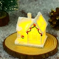 Macro view of glowing white resin Christmas village house with warm LED lights and snow decor - Style D