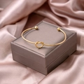 Detail of a polished gold knot open bangle on luxury silk champagne fabric - Knot Style (S281-1)