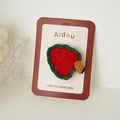 Close-up of a handmade crochet strawberry hair clip with intricate yarn texture detail - Christmas Strawberry