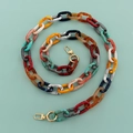 Overhead view of colorful acrylic chain with gold lobster clasps on mint background - Threaded Mixed Colors