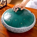 Dark green steel tongue drum with decorative rope being played by hand on wooden desk - 13 Inch 15 Notes - Stone Green - Maple Leaf