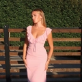 Slim fit light pink dress with ruffle V-neck and tie-up front in outdoor garden setting - S / Pink