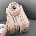 Thick beige winter scarf with fringe trim shown on a gray sofa in a cozy interior - 68x180cm / Beige