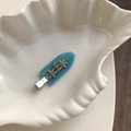 Barrette bleu ciel avec fleurs métalliques et strass colorés sur un plateau coquillage - Bleu