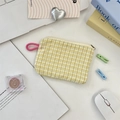 Macro detail of yellow checkered fabric pouch with pink handle on a white desk - Yellow