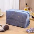 Kosmetiktasche aus blauem Samt mit goldenen Sternen auf einem Holztisch - Blau