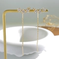 Detail of gold star tassel earrings with white zircon accents on a professional display stand - Triple Star Rhinestone Luxury Style (N-374)