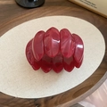 Detalle de pulsera elástica de acrílico rojo oscuro con textura de mármol en una bandeja - Rosa Rojo