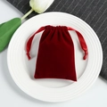 Detail of a red velvet drawstring pouch on white ceramic plate with silk ribbons - 5*7cm / Burgundy