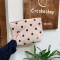 Polka dot corduroy makeup bag held by hand featuring a woven brand tag and zipper detail - Apricot Polka Dot