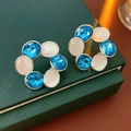 Macro shot of vintage round earrings with blue crystals and cat eye stones on green box - Silver Earring Post-Blue