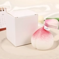 Realistische rosa Pfirsich-Duftkerze mit einer minimalistischen weißen Geschenkbox - Weißer Pfirsich