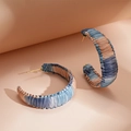 Detail of woven C-shape earrings in blue and pink raffia with gold metal posts - Blue