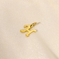 Detailed view of a 14K gold plated letter H pendant on a soft beige silk fabric surface - Letter-H