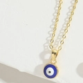Makroansicht der goldenen Evil Eye Halskette mit blauem Emaille-Anhänger auf Weiß - Königsblau
