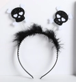 Detail of Halloween headband featuring spring-loaded skulls and white feather trim decor - Black Feather Glitter Skull
