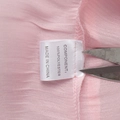 Detailed macro shot of the 100% polyester fabric care label on a pink chiffon dress - Pink (100% Polyester)
