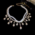 Macro shot of double-layer pearl necklace with rhinestone tassel and golden finish - Gold Water Drop Rhinestone Pearl Double Layer