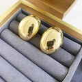 Nahaufnahme von goldenen ovalen Ohrsteckern mit poliertem Finish auf grauem Samt Schmuckkästchen - Gold Groß