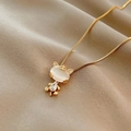 Detail shot of a gold cat pendant with opal and zircons on a wavy silk chain necklace - Gold Catseye Cat