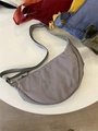 Detail view of a grey nylon crescent crossbody bag featuring adjustable shoulder strap - Gray