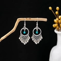 Detail of bohemian silver earrings with turquoise beads and metallic fringe on a branch - Blue