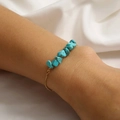 Vintage gold chain bracelet featuring irregular turquoise stones on soft white fabric - Blue Turquoise