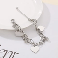 Detail of silver double-layered chain bracelet with heart pendants on a white plate - Steel Color Bracelet (KB153909-Z)