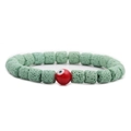 Makroaufnahme grüner Lavasteinperlen und rotem Evil-Eye-Anhänger am Armband - Grüner Lavastein Rotes Böser Blick