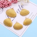 Dettaglio di cinque ciondoli a forma di conchiglia dorata per creazione gioielli DIY - Oro