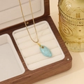 Detail van een druppelvormige turquoise hanger aan gouden ketting in houten doosje - 1# Turkoois Waterdruppel Stijl