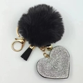 Detail view of black faux fur pompom keychain with rhinestone heart and gold clasp - Black with White