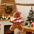 Detail eines Plüsch-Lebkuchenmann-Anhängers mit Spitze und roter Schleife am Weihnachtsbaum - Lebkuchenmann Anhänger (Weiblich)
