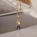 Macro shot of gold-plated princess necklace featuring opal-like stone and purple zircons - Fancy Evil Eye / 23936
