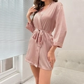 Elegant women's pink satin bathrobe with V-neck and belted waist in a cozy home setting - Pink