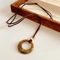 Nahaufnahme eines runden Vintage-Harzanhängers mit Marmortextur an brauner Lederkordel - Brauner Runder Ring-Stil